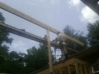 Carpenter setting a ridge beam over a new addition frame — Ice Dam Removal by Roofing Brothers in Maspeth