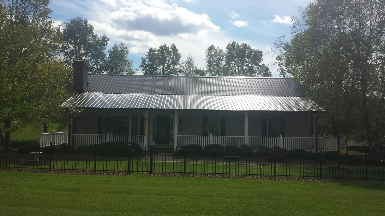 Gray metal roof on a brick ranch with a full width front porch — Gutter Guard Installation work by our crew in Maspeth