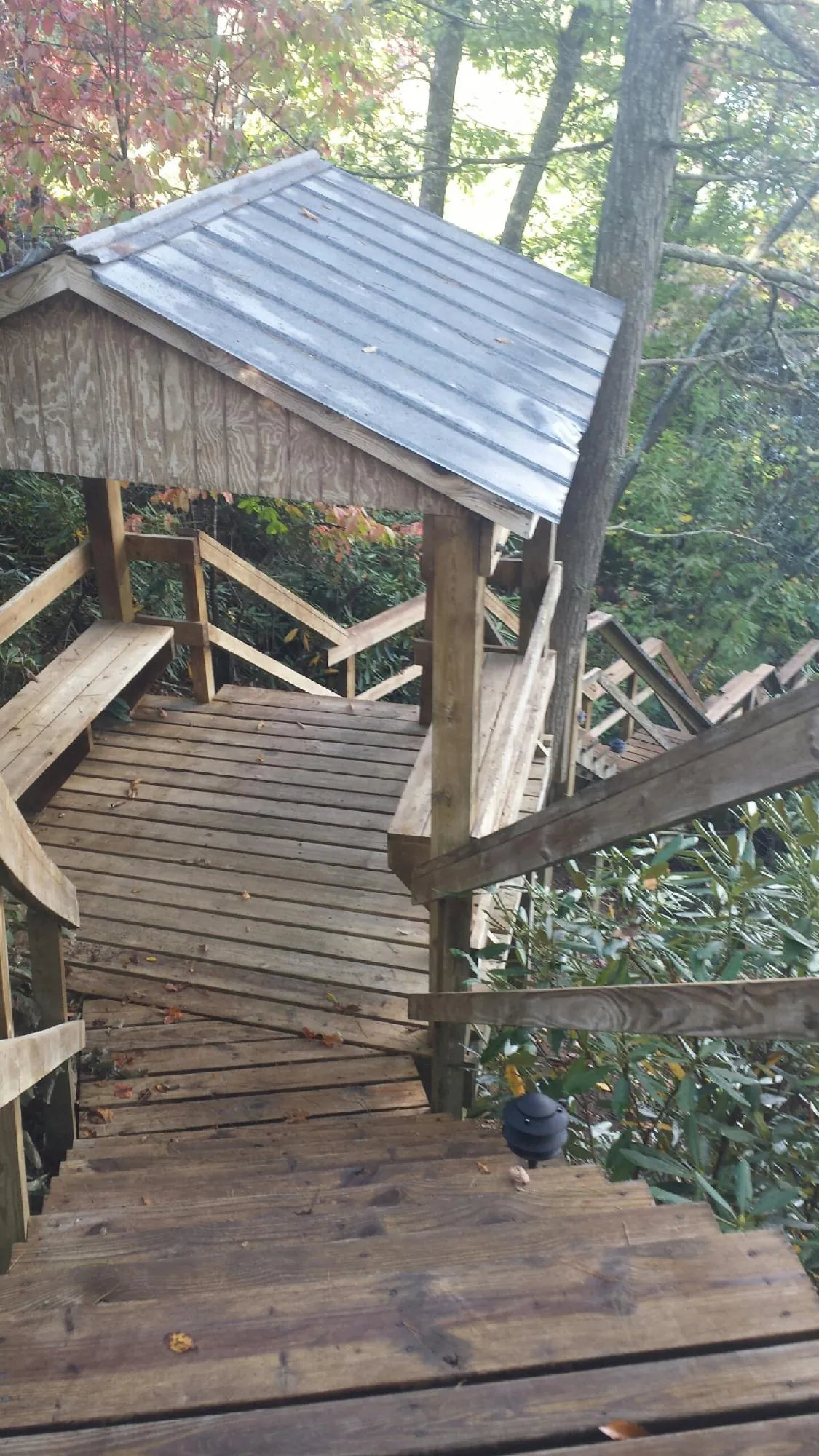 Metal roofed shelter over wooden steps on a wooded walkway — Skylight Repair & Installation work by our crew in Maspeth