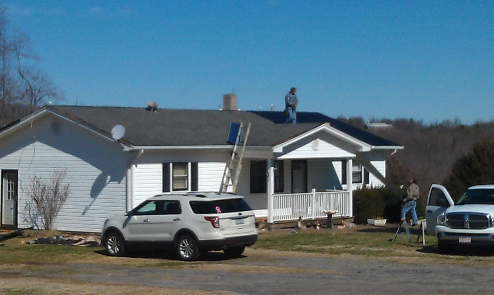 Roofers stripping shingles from a white ranch house roof in Maspeth