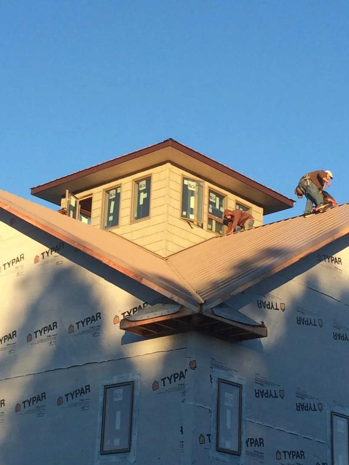Roofers working around a rooftop cupola on a new metal roof at sunset — Roof Waterproofing in Maspeth by Roofing Brothers
